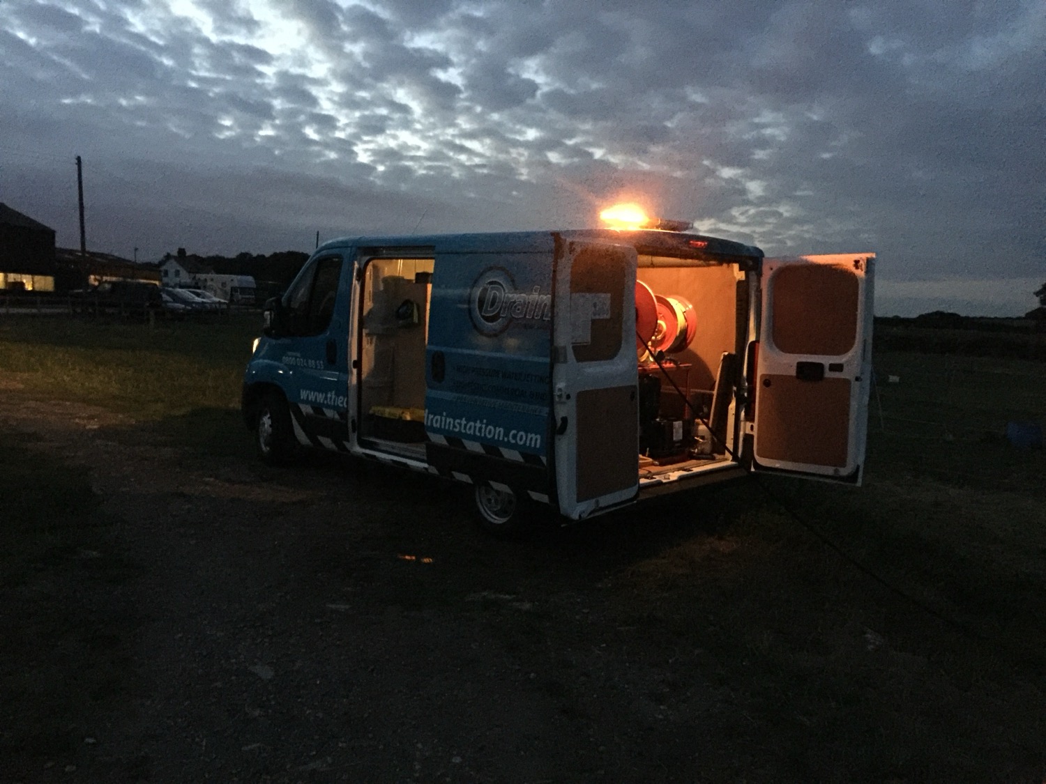 The Drain Station van at dusk with its beacon on and rear doors open